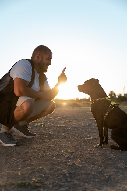 Photo man training his dog outdoors at sunset