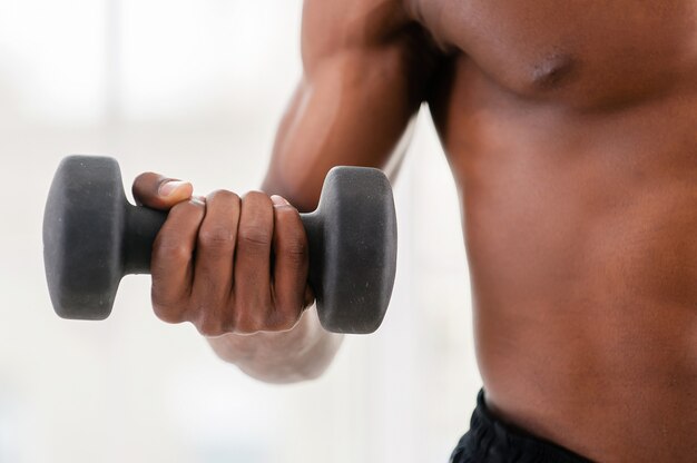 Man training met halters. Bijgesneden afbeelding van Afrikaanse man die traint met halters