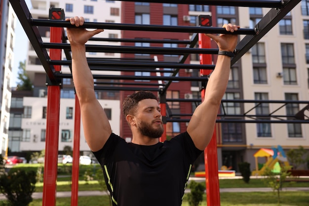 Man training on monkey bars at outdoor gym