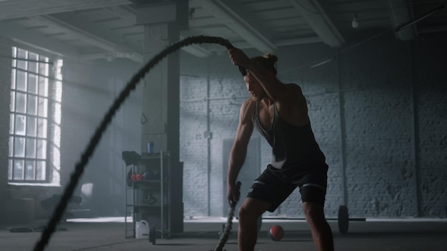 Photo man training with battle ropes in gym athlete doing intensity fitness workout