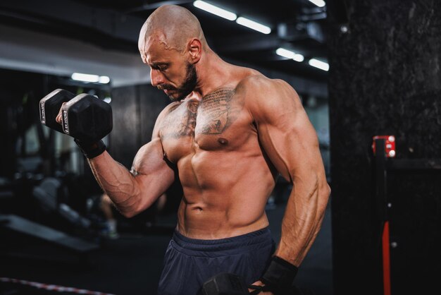 Man traint met dumbbells voor zijn armspieren in de sportschool