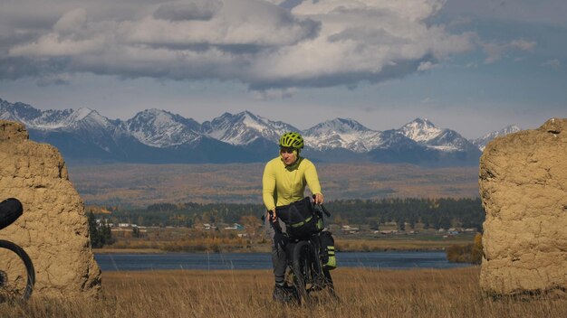 L'uomo viaggia su terreno misto cicloturismo con bikepacking. il viaggio del viaggiatore con le borse della bicicletta. bikepacking da turismo sportivo.