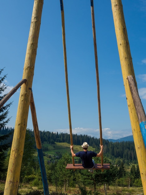 Man traveler enjoying of swinging on heavenly swing and mountain view