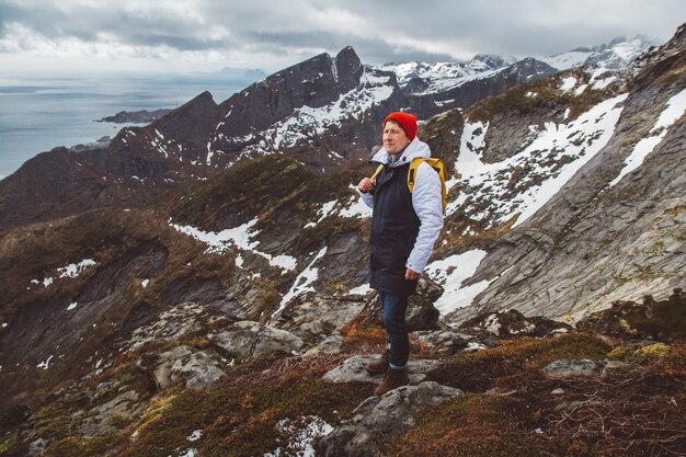 Man traveler hiking on Reinebringen mountain ridge in Norway lifestyle adventure traveling.