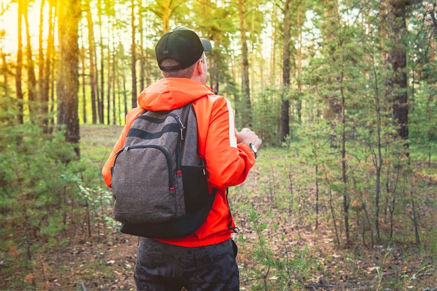 Man traveler walks through the woods. Beautiful wild nature landscape in summer forest. Hiking journey on tourist trail. Outdoor adventure. Healthy lifestyle, leisure activities. Travel, exploration.