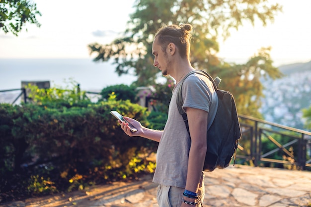 Человек путешественник с рюкзаком, глядя на его смартфон, природу и горы