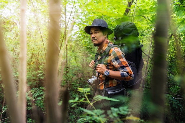 Man traveler with backpack looking to the side walking in the forest