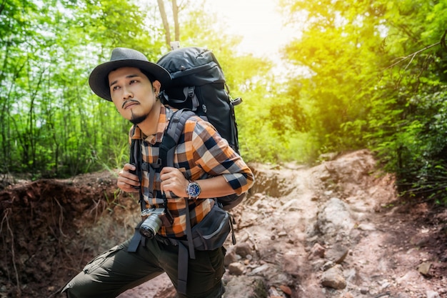 Man traveler with backpack looking to the side walking in the forest