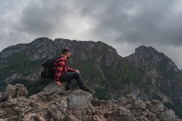 Man traveler with briefcase behind his back high in the Tatra mountains in summer