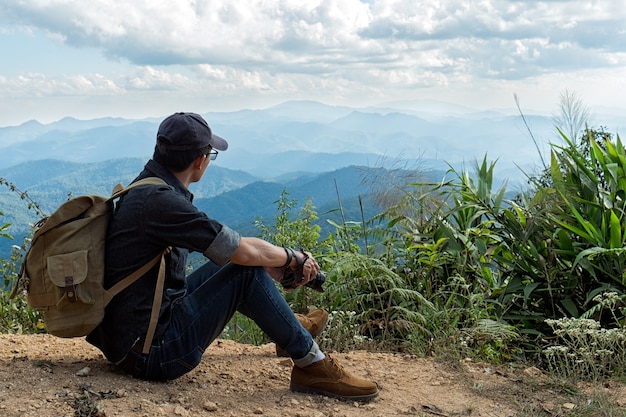 Man Traveler with photo camera and backpack hiking outdoor Travel Lifestyle and Adventure concept.