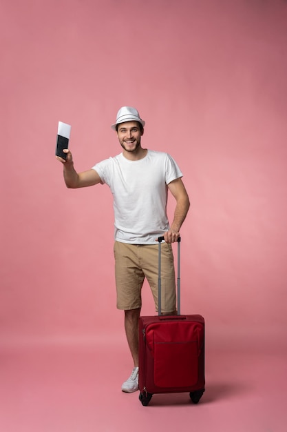 Man traveler with suitcase, passport and ticket on color background.