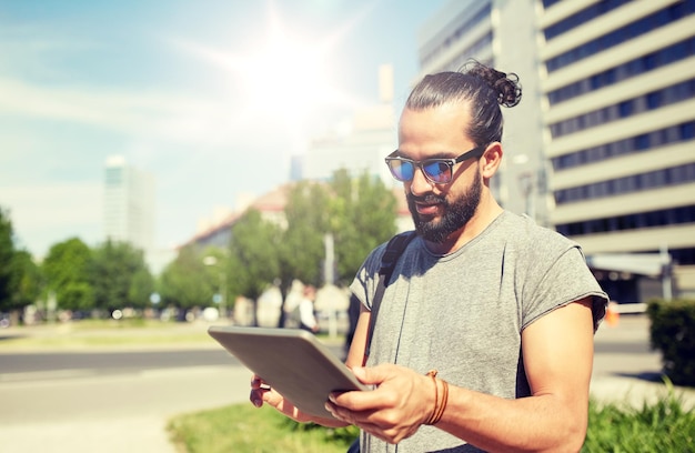 バックパックとタブレット PC を持って市内を旅行する男性