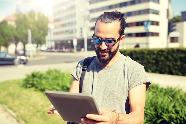 バックパックとタブレット PC を持って市内を旅行する男性