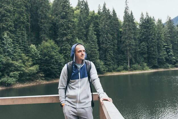 Man traveller looking away standing outdoor near mountain lake. Vacation on nature