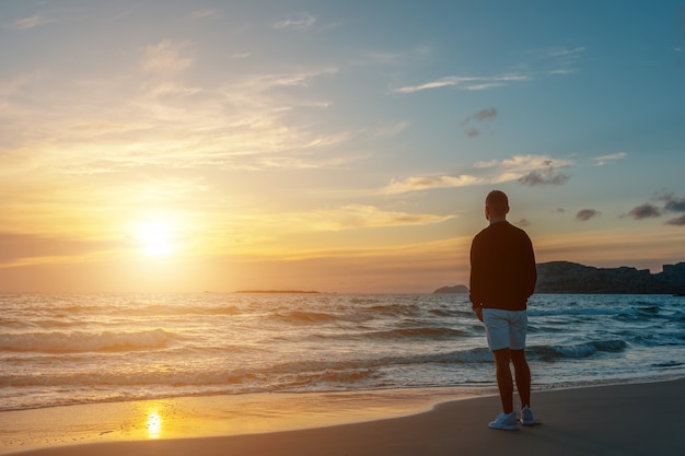 Man traveller on a tropical beach during sunset. Holiday vacation and travel concept.