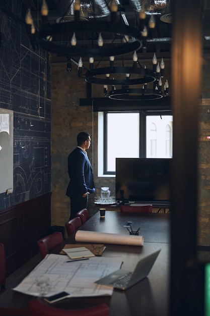 Man in a trendy suit standing in his spacious office