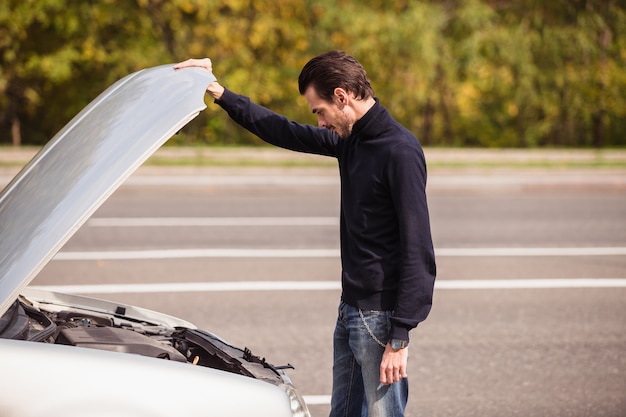 Un uomo cerca di riparare l'auto sulla strada