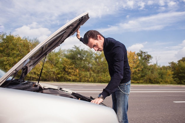 A man tries to repair the car on the road