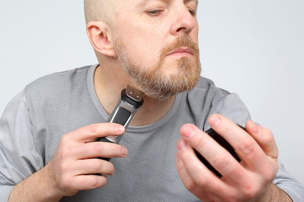 Man trimmer corrects his beard
