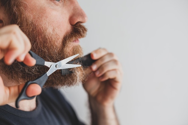 写真 家で剪刀でひげをる男性