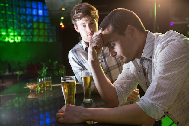 Man troostend zijn depressieve vriend in bar