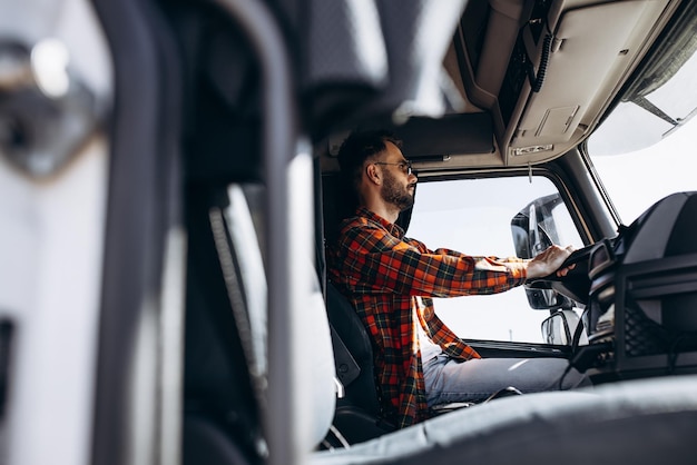 Man trucker driving in a cabin of his truck