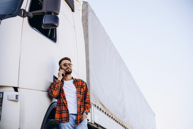 Man trucker praten aan de telefoon bij zijn witte vrachtwagen