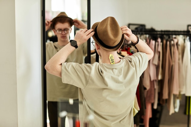 Photo man trying on hat in thrift store and looking in mirror