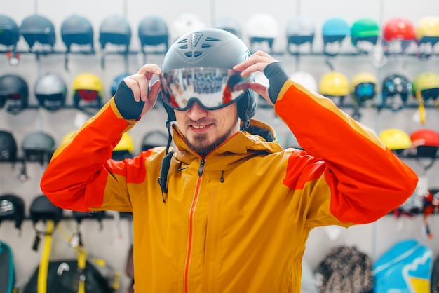 Photo man trying on helmet for ski or snowboarding