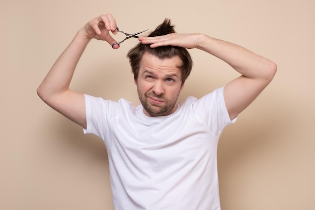 Man trying to make a hairstyle by himself with scissors being on quarantine