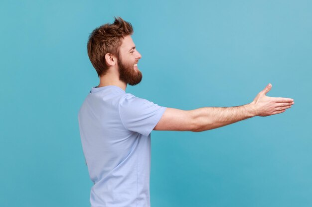 Photo man in tshirt giving hand for handshaking welcoming partners job offer expressing positive emotions