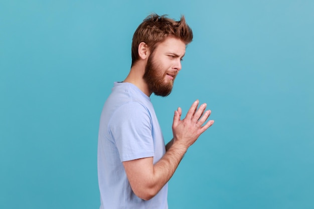 Man in Tshirt schemes something keeps hands together makes plans sly expression looks thoughtfully