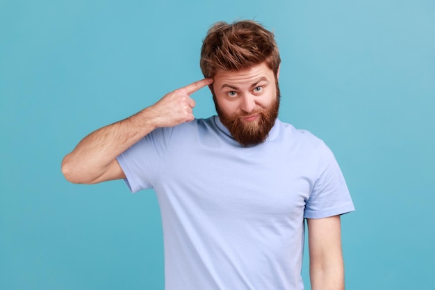 Man in Tshirt showing stupid gesture with finger near head out of mind accusing crazy dumb plan