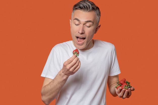 Man in tshirt tasting ripe red strawberry