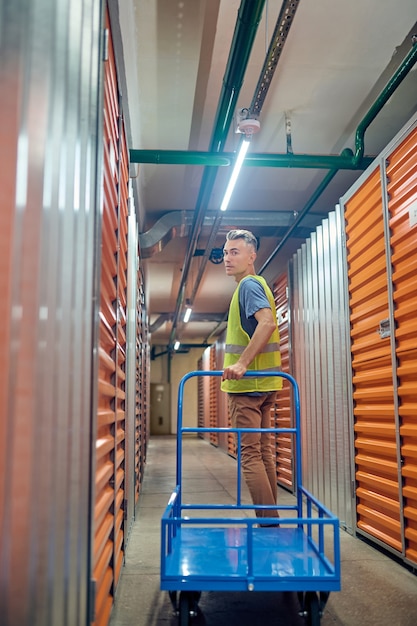 Man turned back with warehouse trolley.