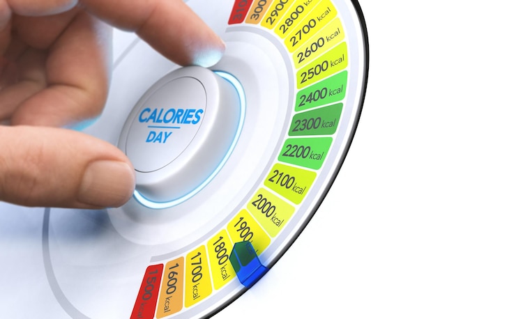 Photo man turning a calorie knob to reduce daily intake level. composite image between a hand photography and a 3d background.