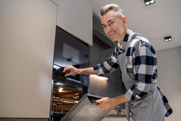 Man turning toggle switch of oven looking at camera