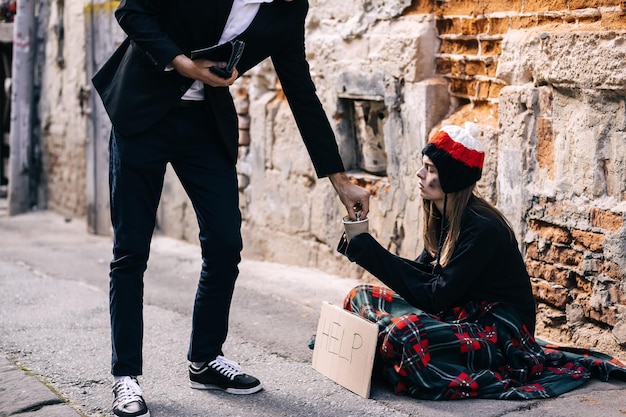 Man in tuxedo came up to beggar to help give money donation Ri