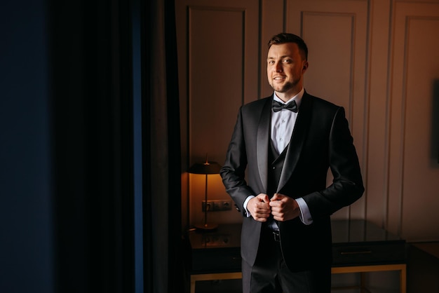 a man in a tuxedo stands in front of a door