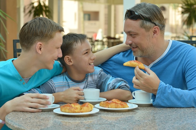 Man and two boys having breakfast on the table