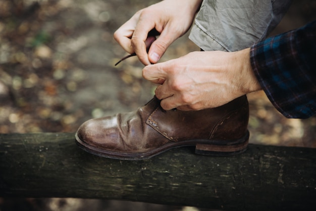 Man tying his leather shoes in the woods