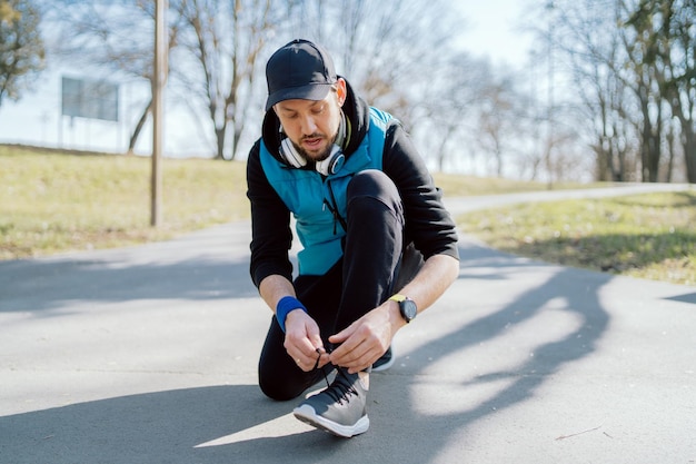 A man tying his running shoes a person running outside on a\
sunny spring day