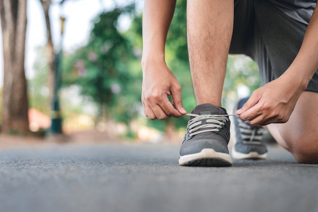 Photo man tying running shoes on the park