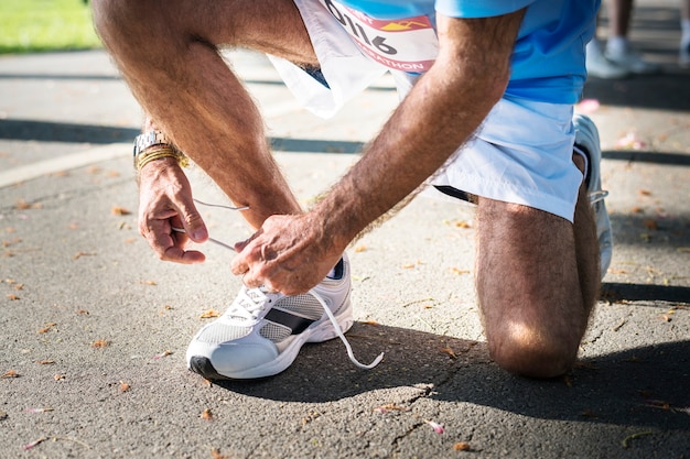 Uomo che lega il laccio delle scarpe alla sua scarpa