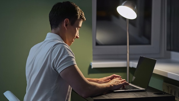 Man types on laptop keyboard in uncomfortable position