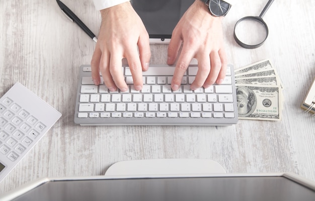 Man typing in keyboard. Dollar banknotes on the desk