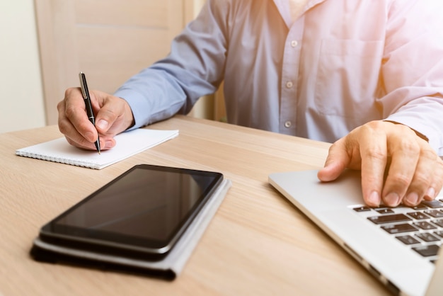 Man typing on laptop and writing