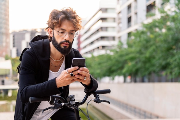 Uomo che digita sul cellulare seduto sulla sua bicicletta