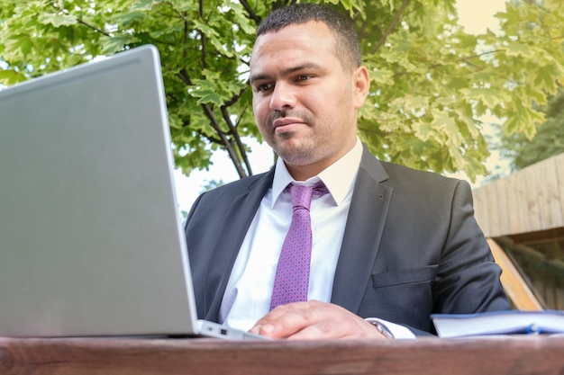 Man uit het Midden-Oosten typt op een laptop Ernstige jonge man in pak en stropdas werkt