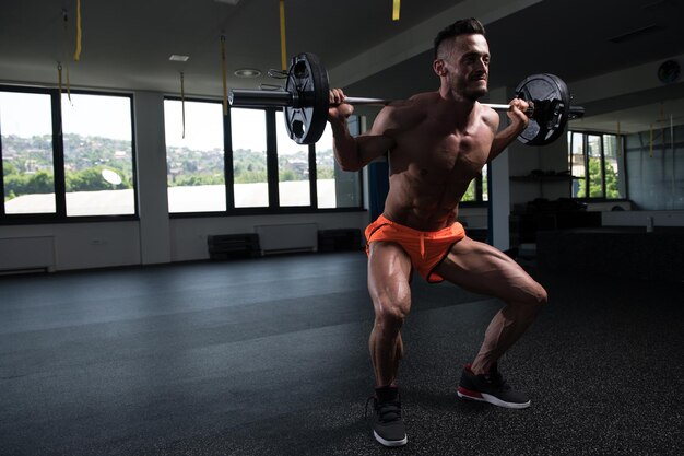 Man uitoefening van benen met barbell in de sportschool